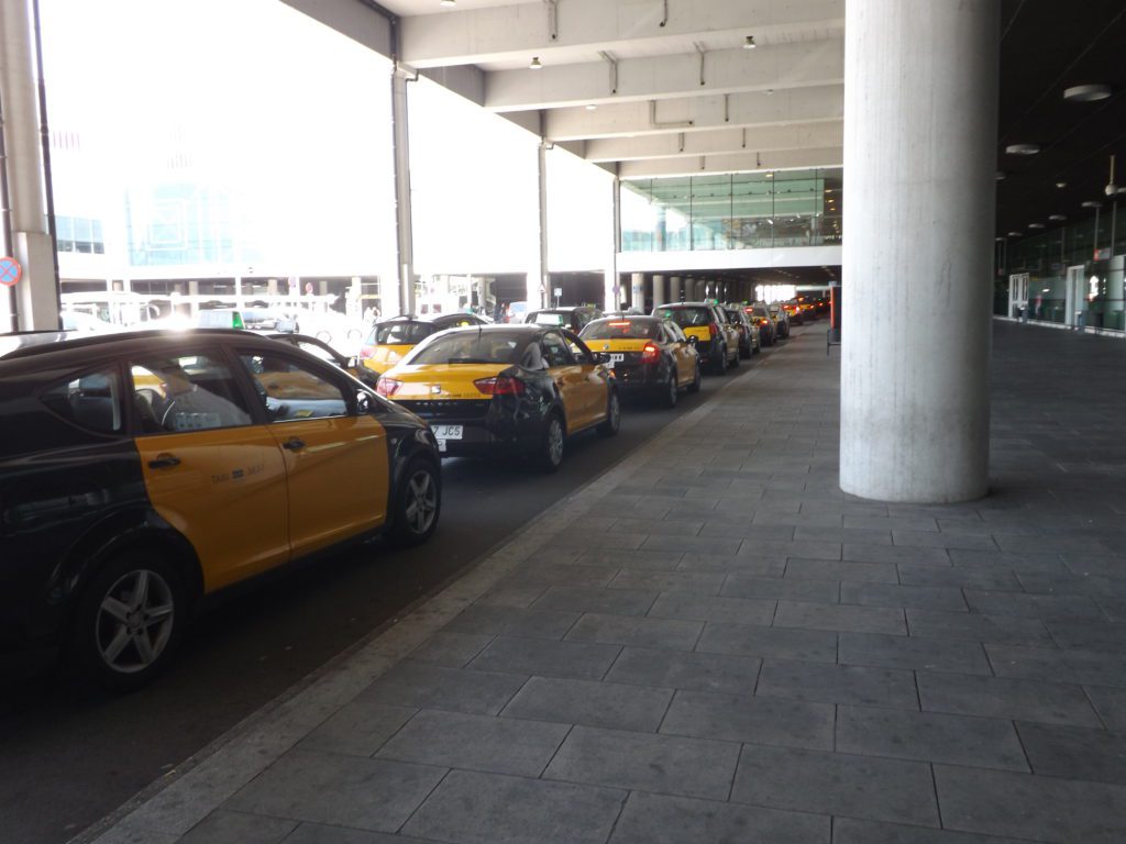 Yellow and black Barcelona Airport taxis lined up outside El Prat Terminal.