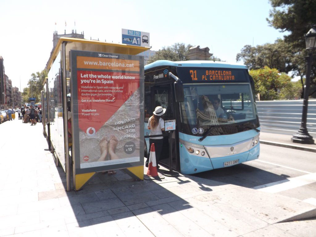A blue and white Barcelona Airport AeroBus waiting at the bus stop.