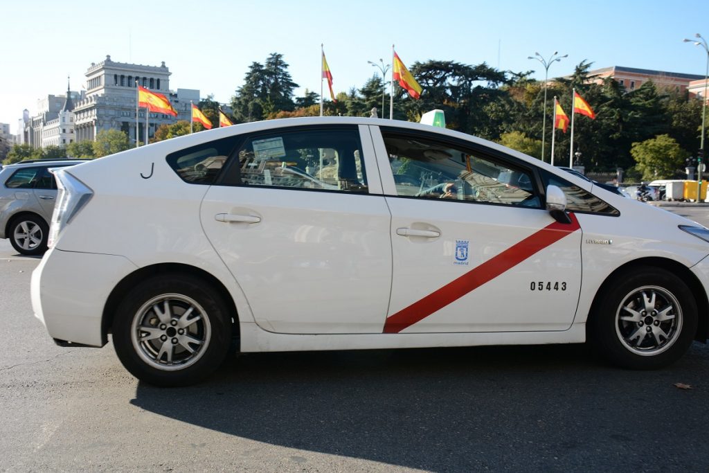 A white Madrid Airport taxi parked outside.