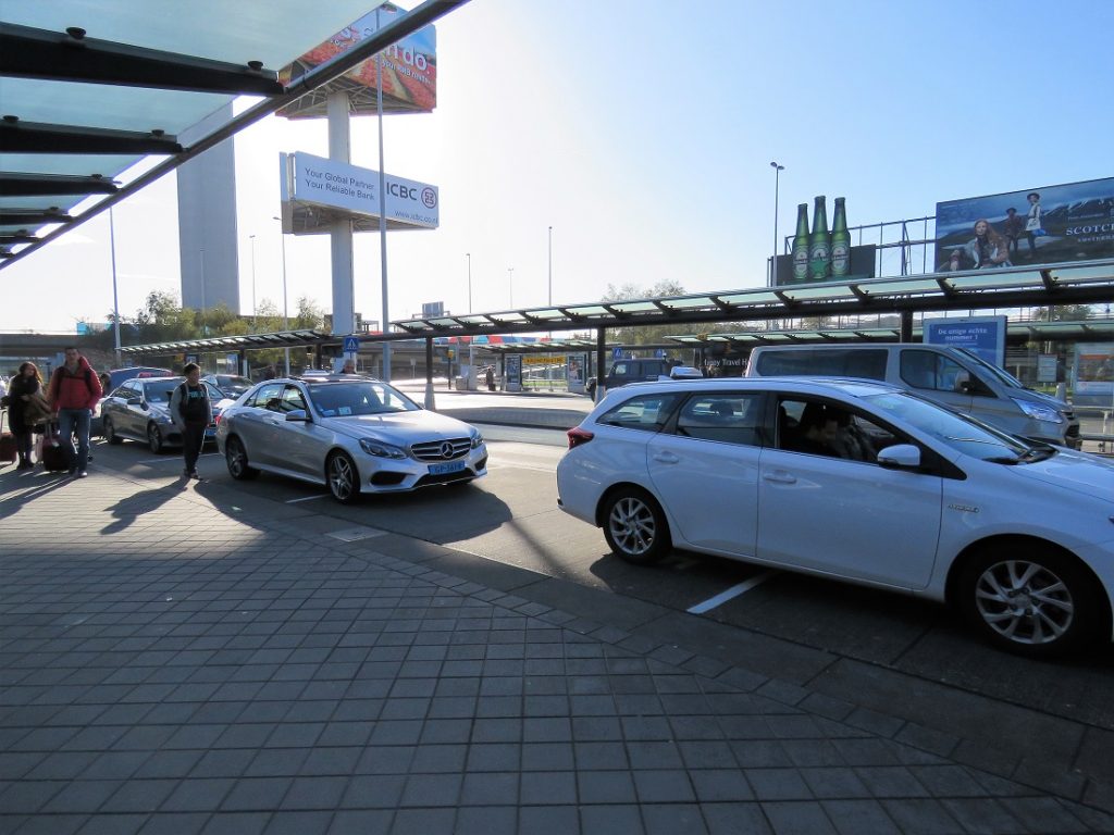 White Amsterdam Airport taxis lined up outside Arrivals.