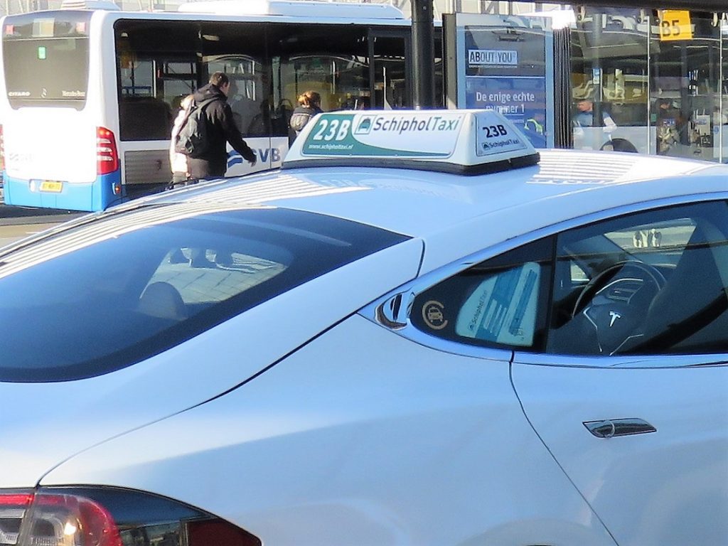 The roof of a white Amsterdam taxi with a 'Schiphol taxi' sign on the top.