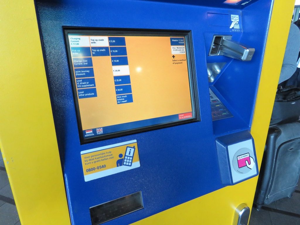 A yellow and blue automated train ticket machine at the airport.
