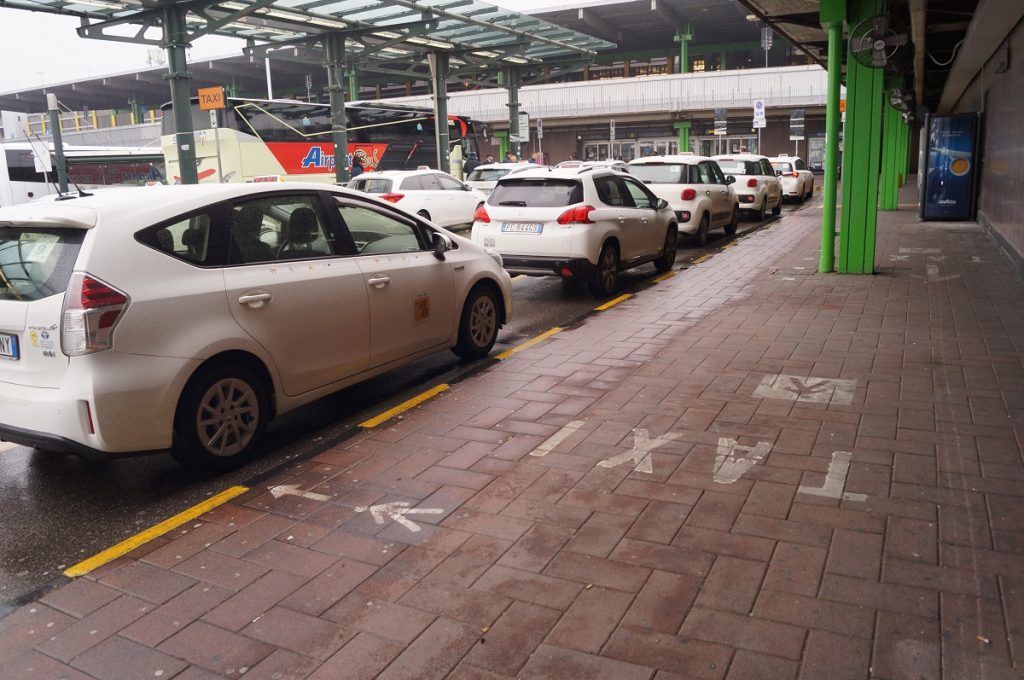 White Linate Airport taxis lined up offering rides from Milan Linate Airport to city center