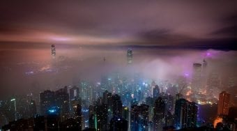 Hong Kong city center lit up at night under a purple haze.