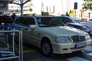 Lisbon airport white and black taxis lined up. Take a taxi from Lisbon Airport to Cascais and start exploring.