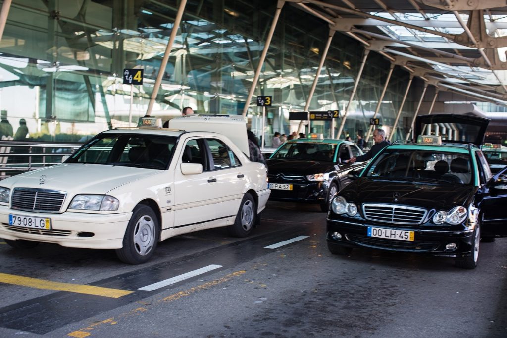 White and black taxis lined up in the official taxi rankat Lisbon Airport.