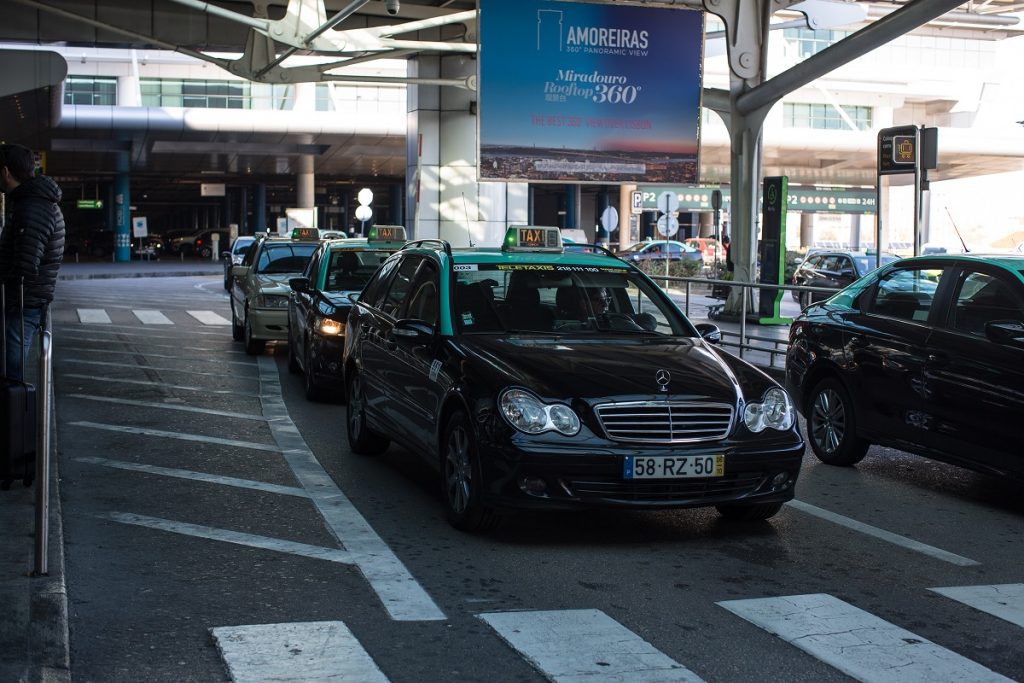 White and black taxis lined up outside Lisbon Airport.