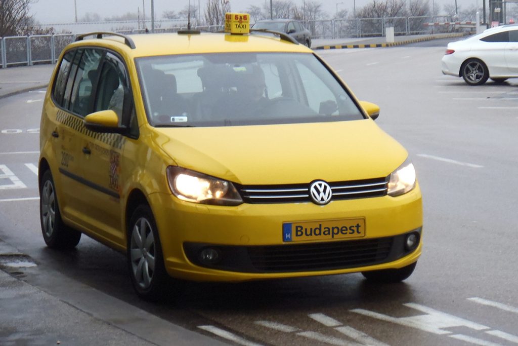 A yellow Budapest taxi driving on a street in Budapest city center