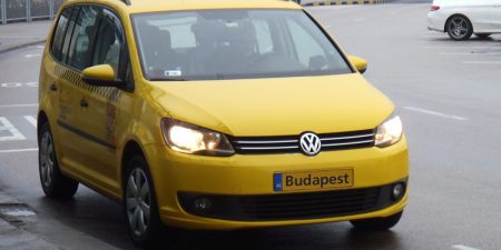 A yellow Budapest taxi driving on a street in Budapest city center
