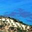 Aerial view of Laganas, Zakynthos - A white beach with greenery bordering a clear-blue sea.