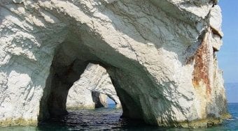 White rocks in turquoise waters with an arch through the centre.