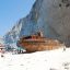 Photo of the shipwreck on Navagio Beach, surrounded by tourists and with cliffs behind.