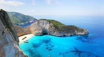 Aerial view of Shipwreck Beach from the cliff high above, showing a white-sand beach with turquoise blue waters.