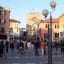 A photo of Mestre Train Station, with people on the streets and a clock tower in the background.