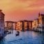 View of a Venice canal lined with pretty buildings with a sunset sky above.