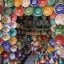 A man sitting inside a Moroccan ceramics shop with colourful bowls all over the walls.