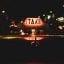 A glowing taxi roof sign on top of a taxi at night.