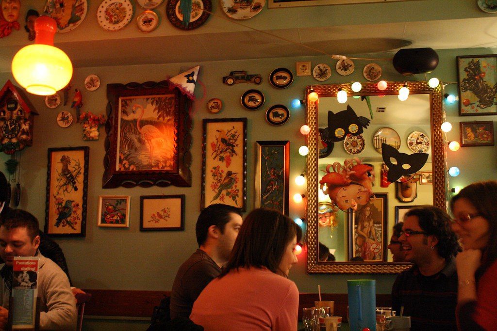 thessaloniki cafe at night. People chatting and lights around many picture frames.