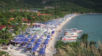 beachfront in Pattaya covered with beach umbrellas and boats in the water