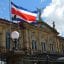 San Jose National Theatre with a Costa Rican flag flying in front and blue skies above.