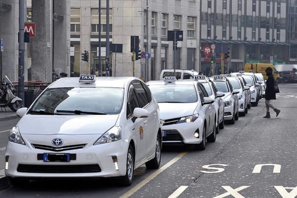 A white taxi in Milano, parked in a rank of official Milan taxis.