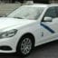 Malaga taxi that is white with a blue stripe.