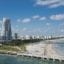 Coastline of Miami beach, sky towers, and bridge under a cloudy blue sky.