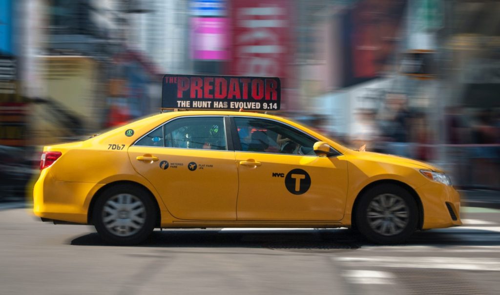 Side view of a yellow cab driving through New York City.