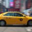 Side view of a yellow cab driving through New York City.
