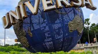 The Universal Studios sign, a large blue globe with 'Universal' lettering wrapped around it, with lots of greenery around it.
