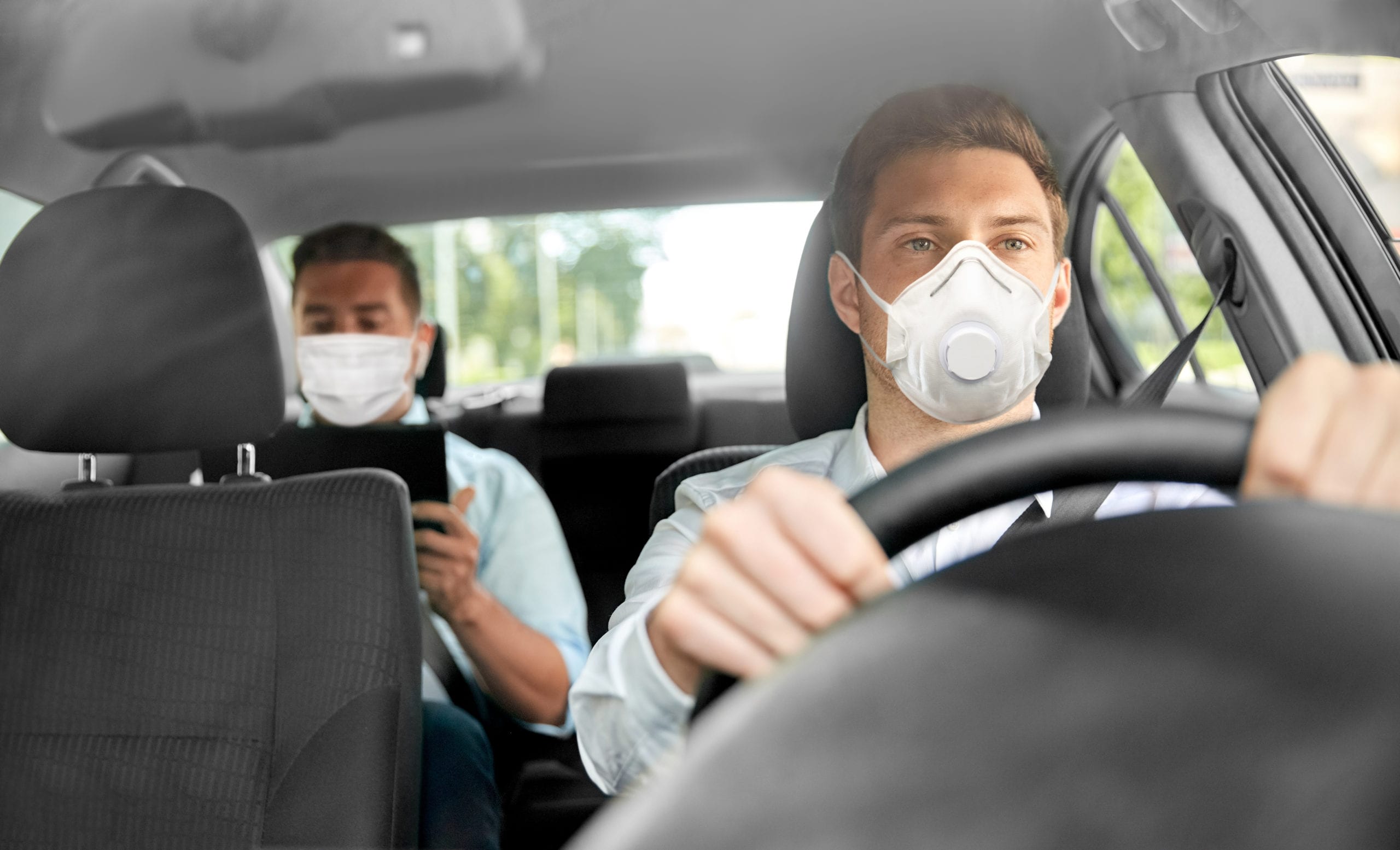 driver and passenger in car wearing protective masks