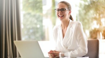 woman in front of laptop looking up and smiling