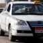 white car with black and white checked strip on the side and yellow taxi sign on roof in Cairo egypt