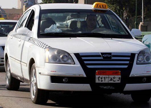 Cairo taxi white car with black and white checked strip on the side and yellow taxi sign on roof in Cairo egypt