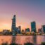 Ho Chi Minh City skyline, showing skyscrapers and smaller buildings, with water in front and an evening sky above.