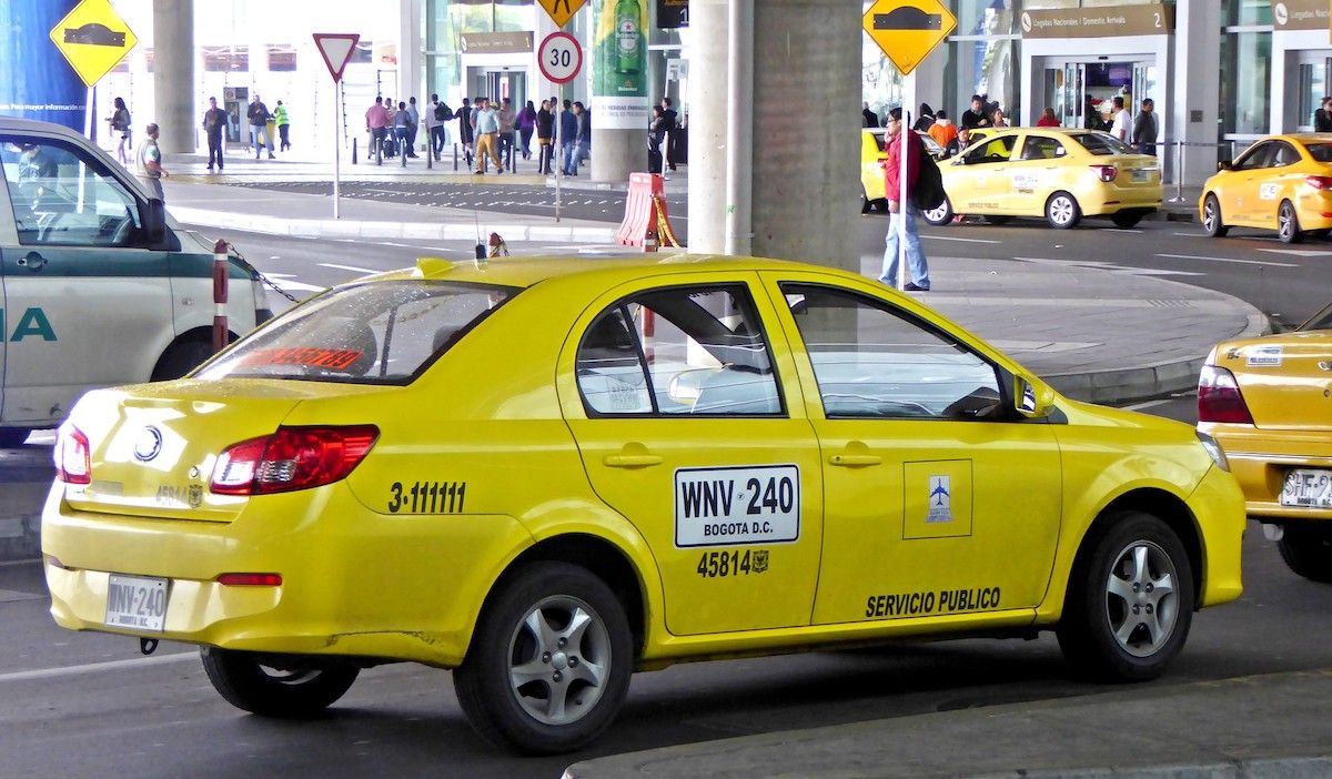 taxi-bogota yellow taxi with black and white sign on the back door