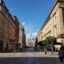 view between two beige buildings down a courtyard leading to a building with a peak