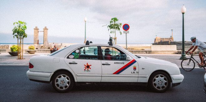 white taxi car with red and green stripe on the front door and logo on the back door in Lazarote, Spain