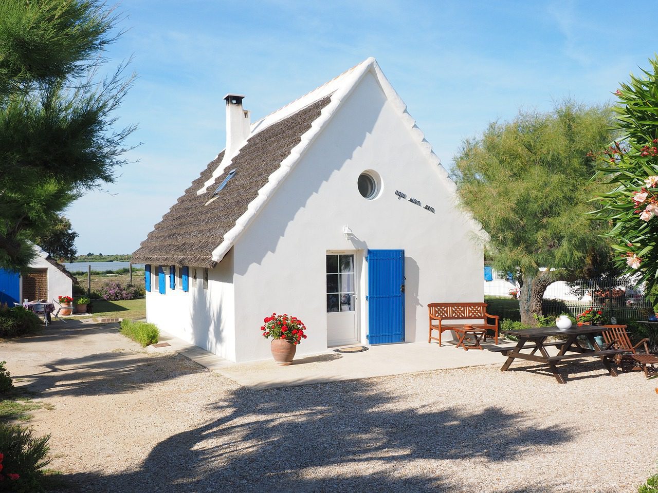 small white house with slanted roof and blue door and window shutters