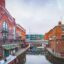 red and brown brick buildings by canal under cloudy sky in daytime