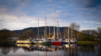 red green blue and yellow coloured boats in body of water on a cloudy day