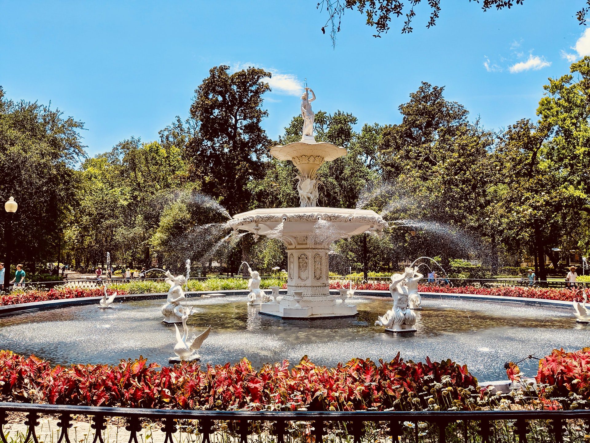 The famous fountain in Forsyth Park, surrounded by an iron gate and oak trees.