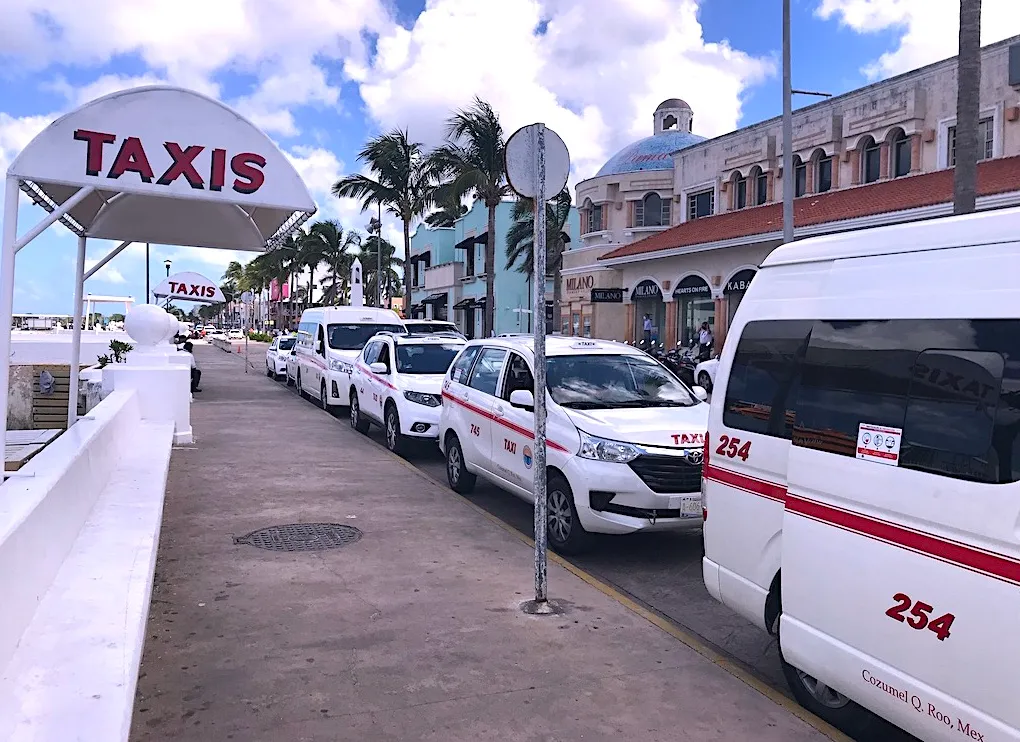Cozumel taxi rank line of white taxis with red details waiting by an allocated Taxi area