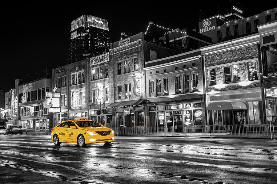 Nashville taxi black white and grey concrete buildings with a bold yellow taxi driving in the street standing out