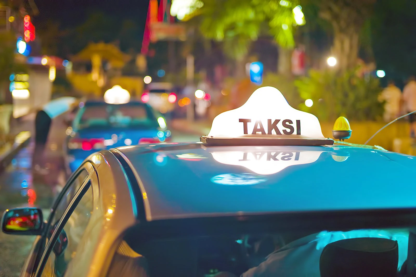 Bali taxis A blue Bali taxi with lighted Taksi signage on the roof.