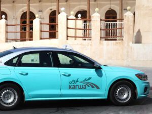 neon blue coloured taxi with white and black taxi sign on the roof in front of concrete building