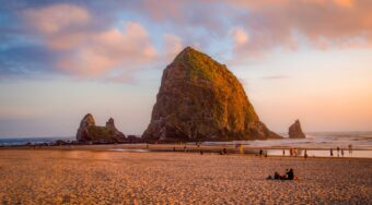 rock formations on sea shore and people hanging out on the beach