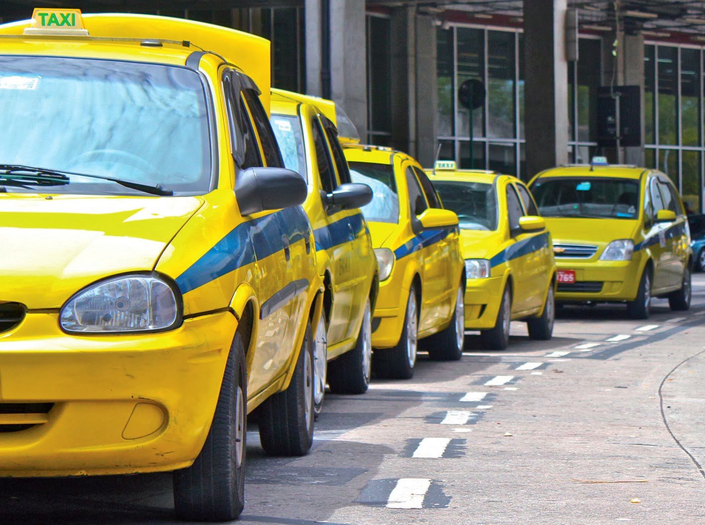 Rio Taxi yellow taxis with a blue line and a signature yellow sign with green letters on the roof lining up
