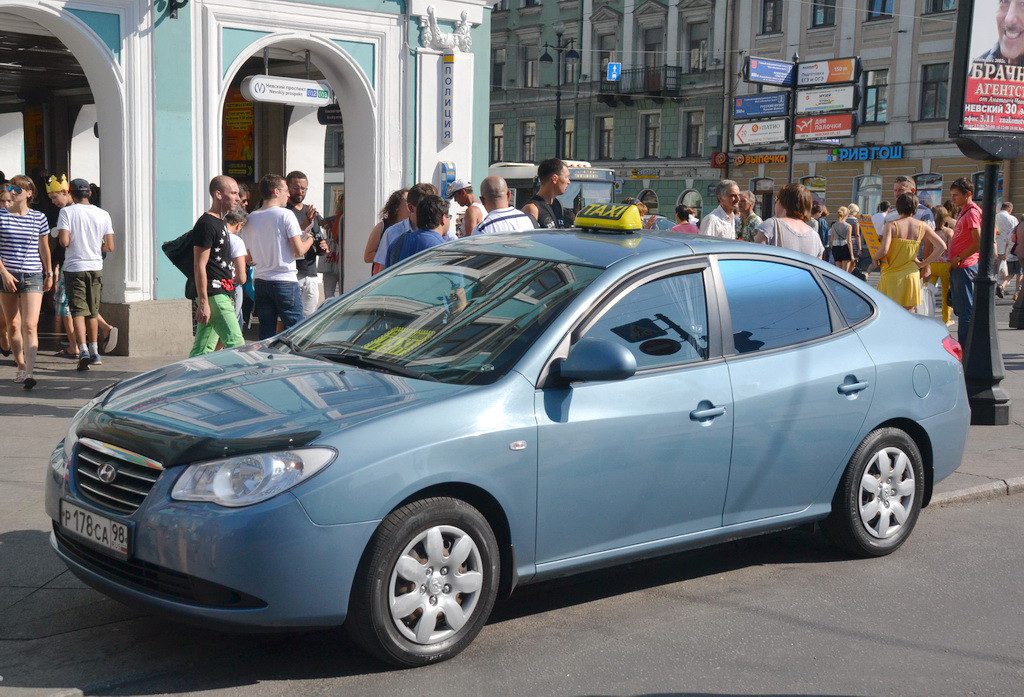 Saint Petersburg taxi silver-blue vehicle with signature yellow and black taxi sign on its roof parked near a busy city street