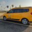 large dark yellow taxi vehicle parked on the side of the street near field